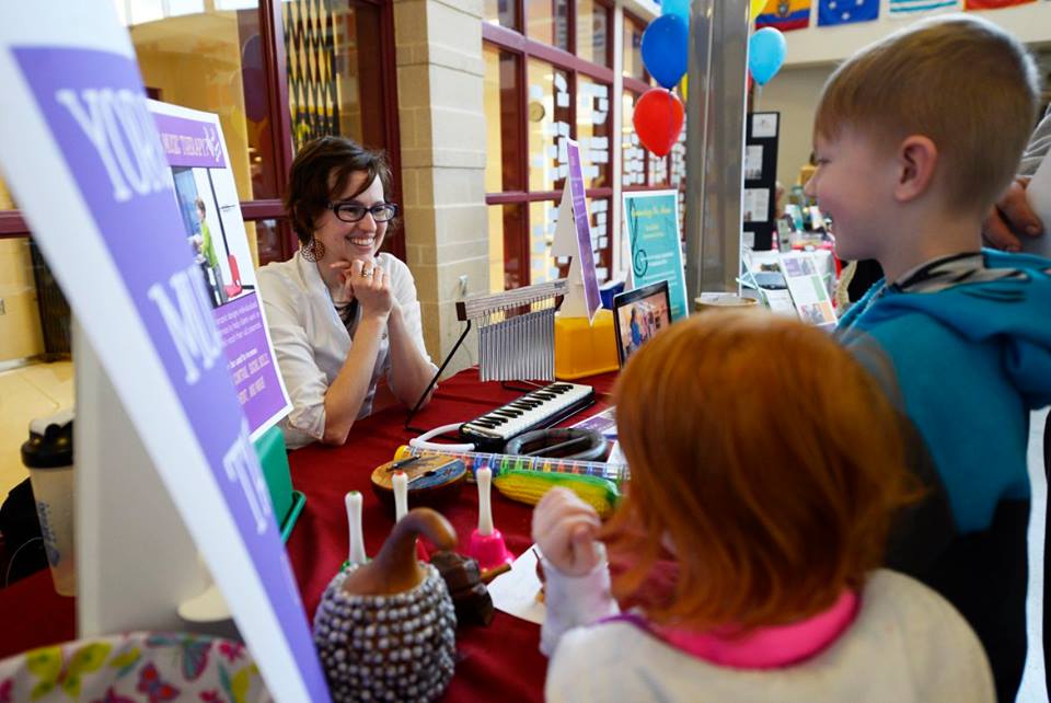 Music therapist greeting young potential clients at a mental health fair.